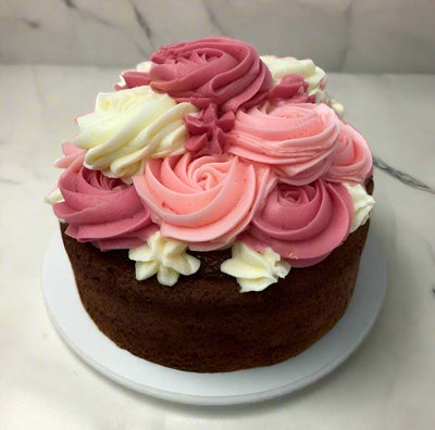 A chocolate cake with white and pink icing served on a white plate.